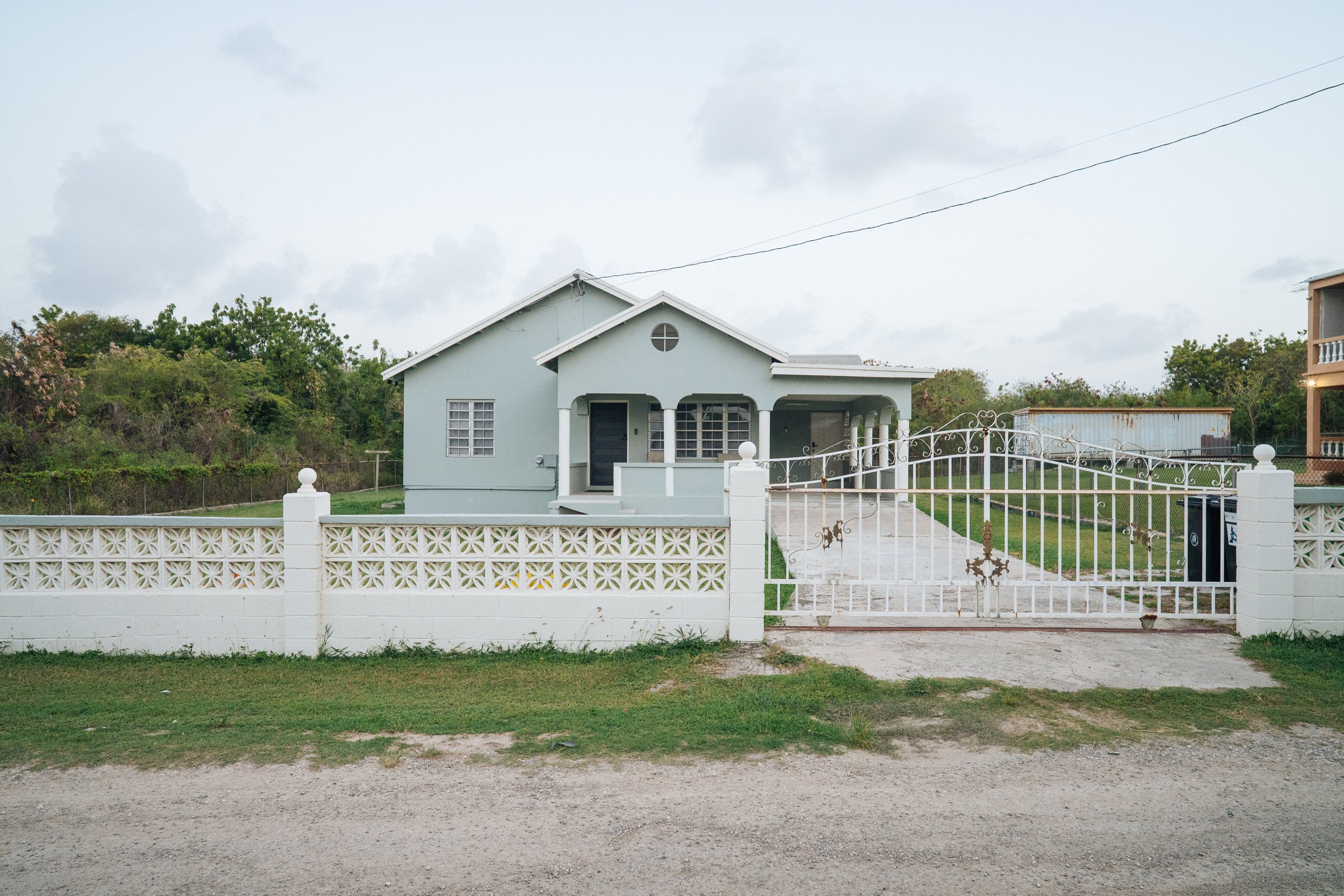 Pale blue bungalow with a front veranda and a gated garden