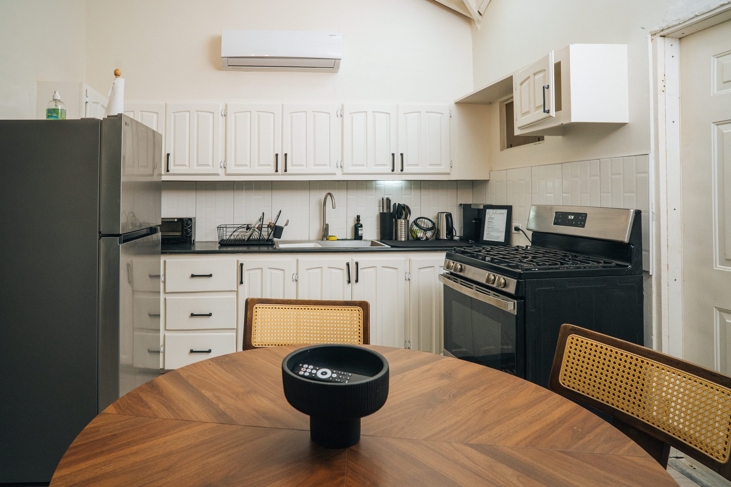 Full kitchen with white cabinets, refrigerator, oven, and a round wooden dining table