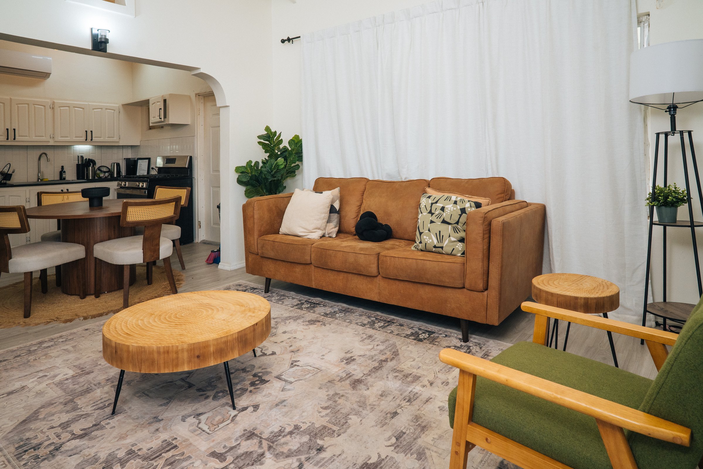 Living room with a caramel sofa, round wooden coffee table, and green accent chair